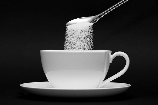 Sugar being poured into a coffee cup